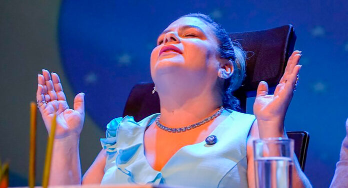 A prefeita Flávia Pascoal levanta as mãos ao alto enquanto fecha os olhos (Foto: reprodução PMU)