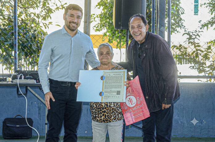 O prefeito Zé Louquinho (à direita) entrega documentação de posse para moradora do Sonho Meu 4